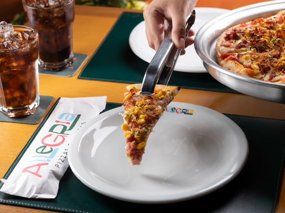 Fatia de pizza servida sobre o jogo americano da Allegria
